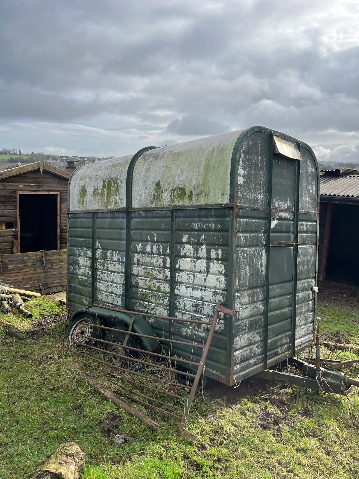 The original weathered green horsebox in a farmyard, before it was converted into the Tipsy Daisy bar